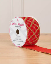 A spool of red ribbon with gold lines on a wooden table against a light background 