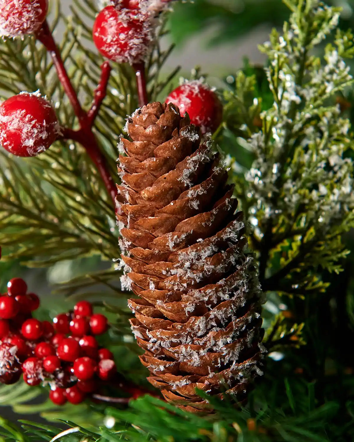 Additional close-up of frosted red berries and pinecone pick highlighting pinecone detail