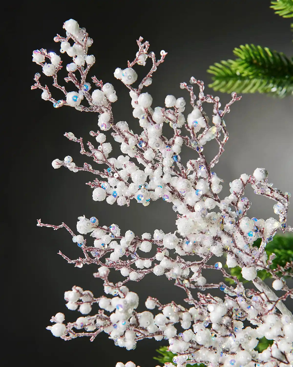 Alternative close-up image of white pearls crystal spray attached to Christmas tree in front of grey wall background
