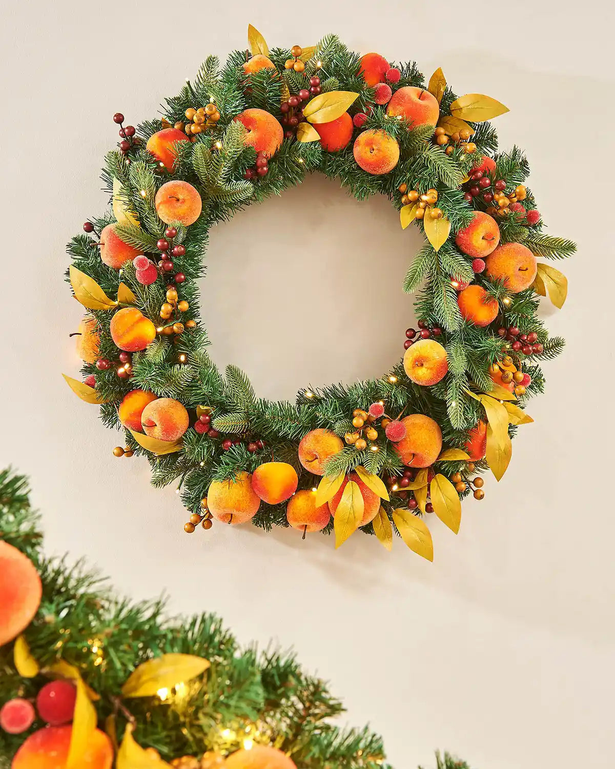 Artificial Oranges and peaches on a wreath against a cream background