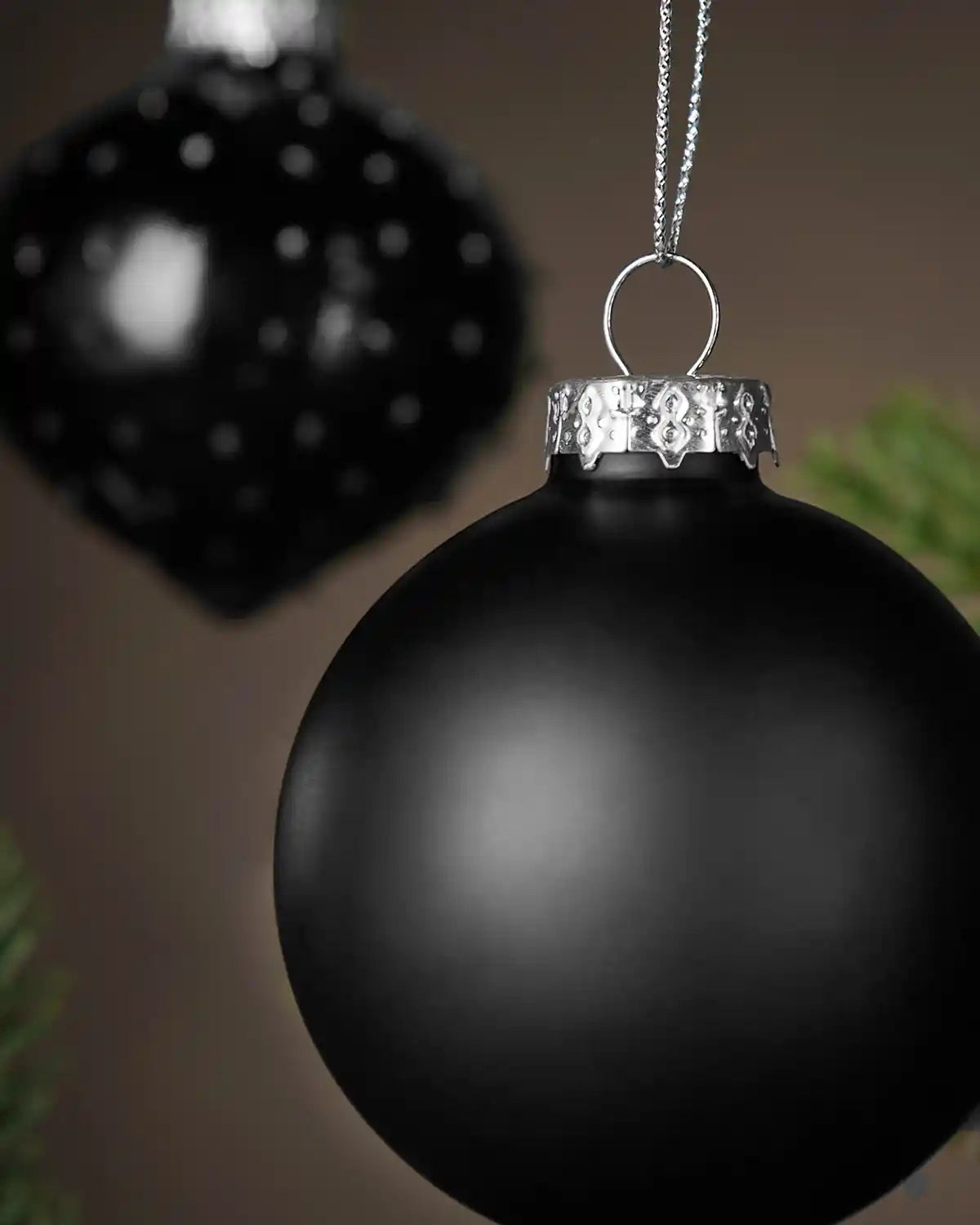 Black Christmas bauble with silver cap on a blurred background