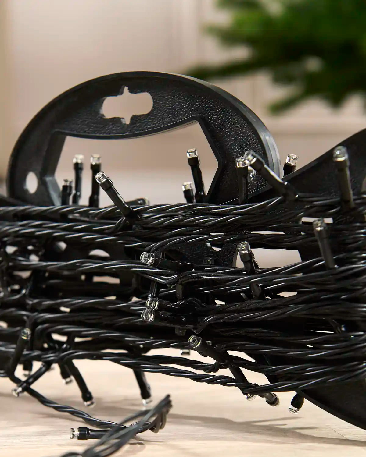 Black Christmas string lights with small clear bulbs, coiled with black plastic hangers and clips visible in the foreground and background.