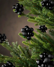 Black berry cluster baubles on a tree with a brown blurry background
