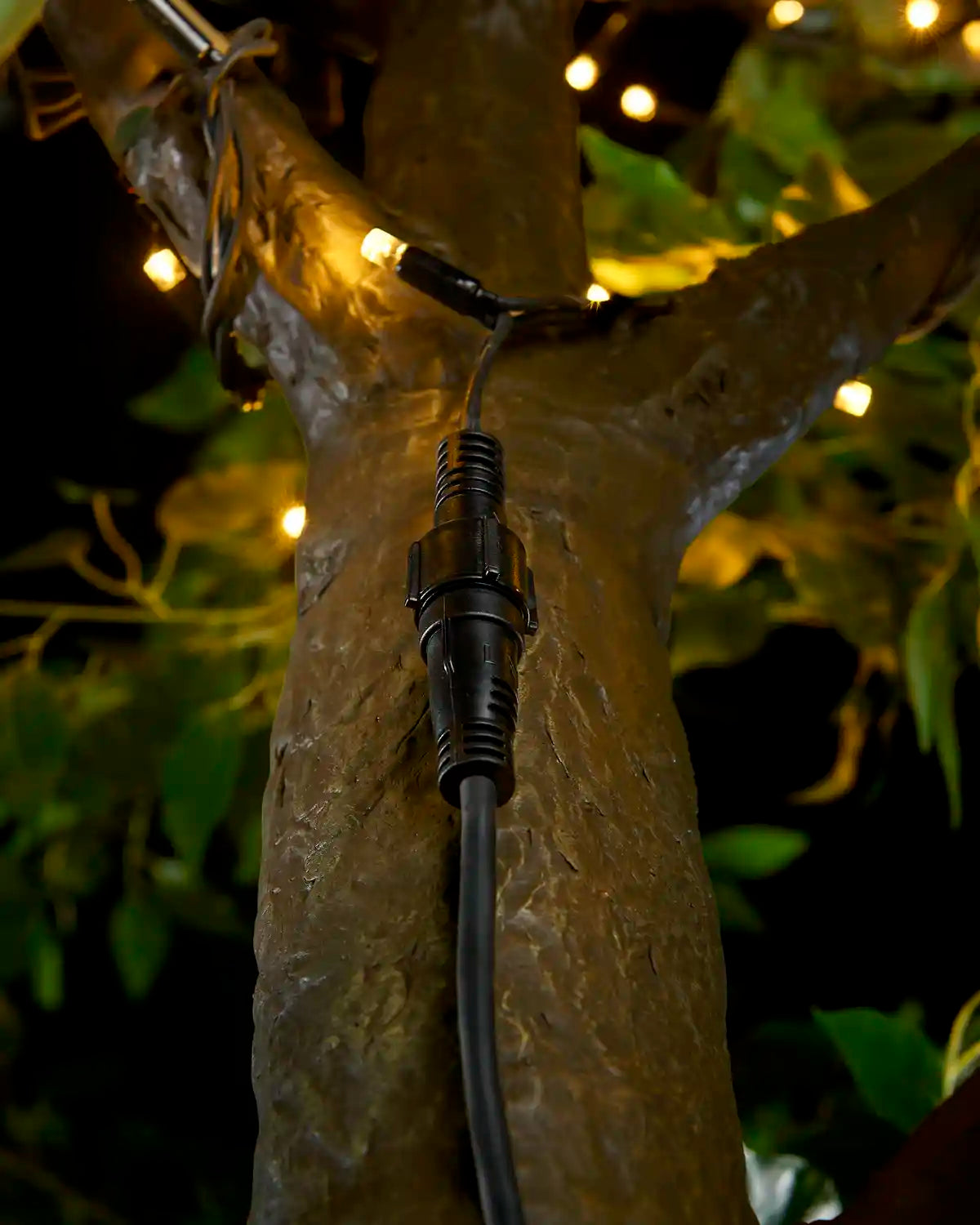 Black Pro Series connectable extension cable connected to string lights around a tree