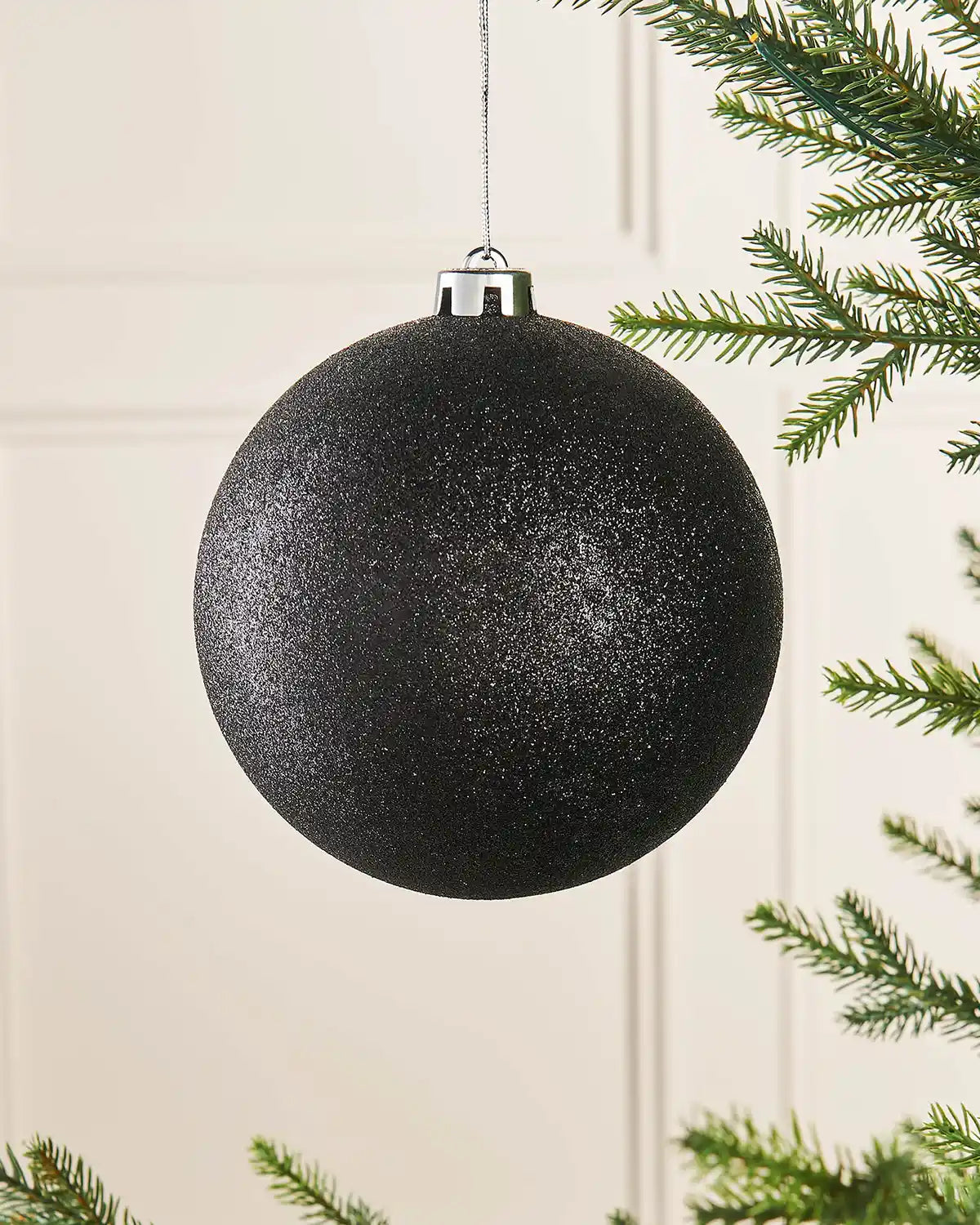 Black glitter oversized 15cm bauble on a Christmas tree branch