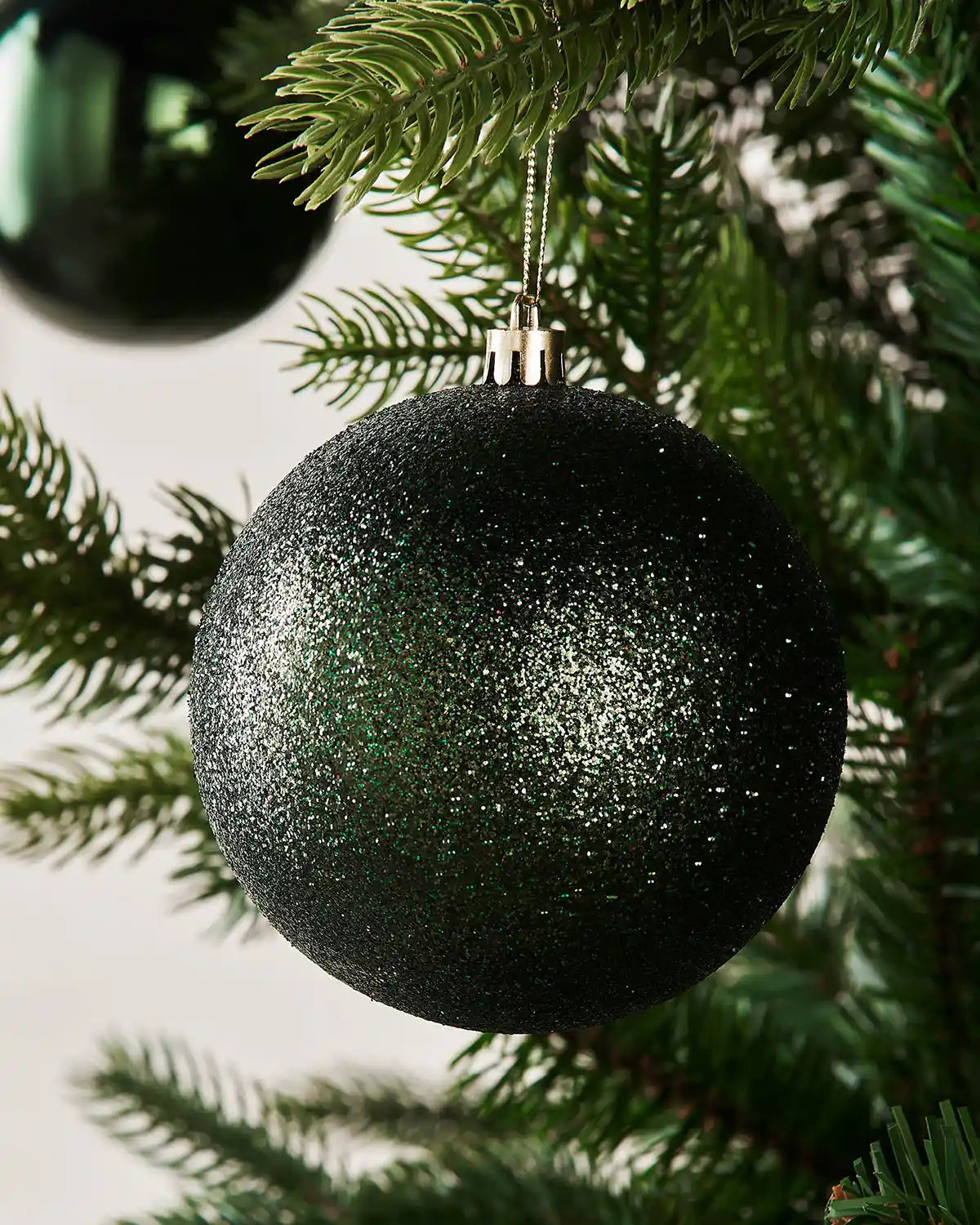 Black glittery Christmas baubles hanging on a tree