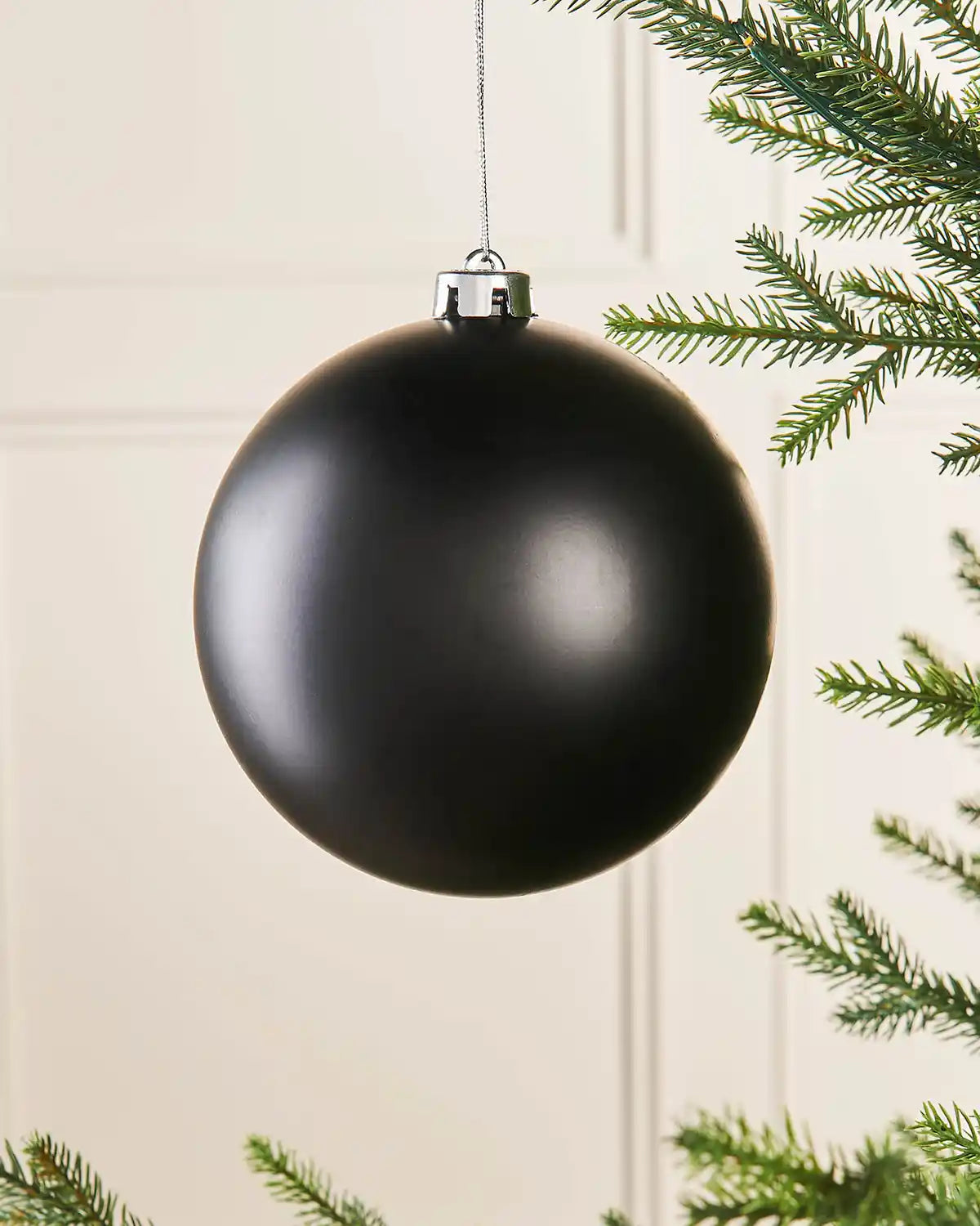 Black matt oversized 15cm bauble on a Christmas tree branch