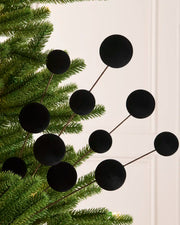 Black velvet bauble Christmas tree pick on a Christmas tree against a light background