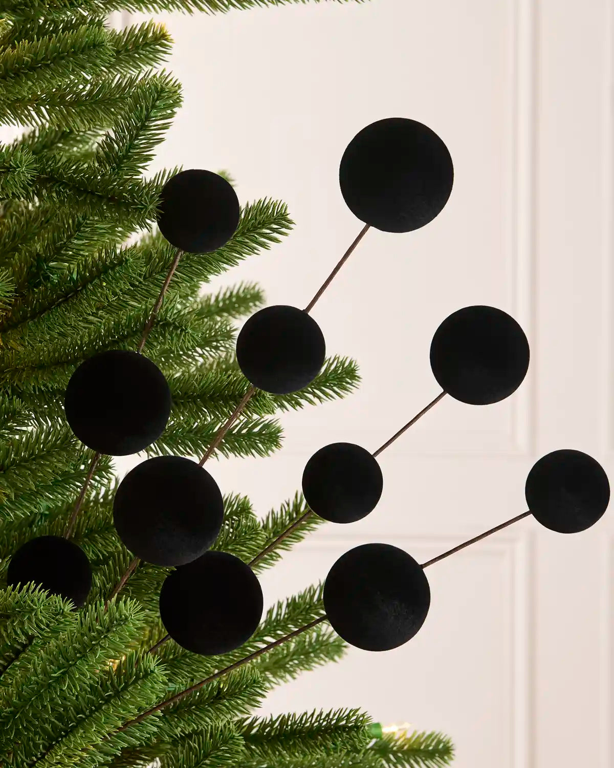 Black velvet bauble Christmas tree pick on a Christmas tree against a light background