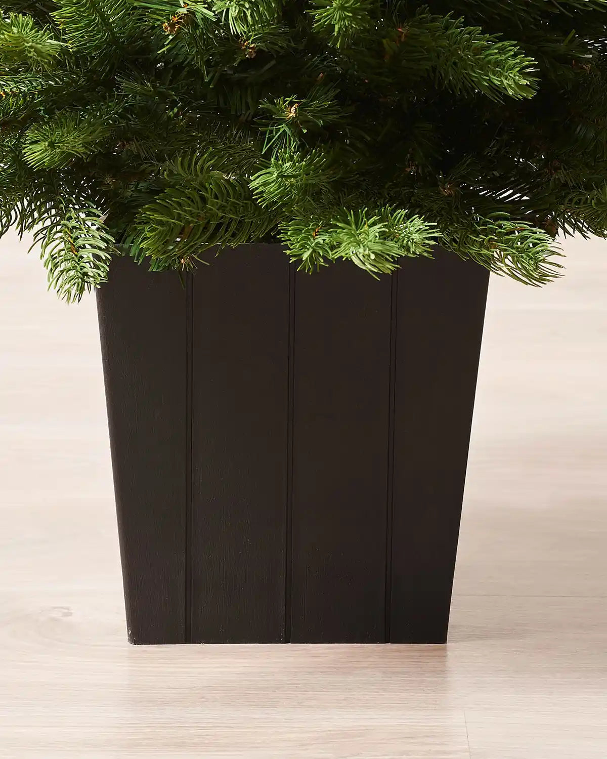 Black wooden style pot for Christmas tree on a light wooden floor 