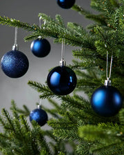 Blue Christmas baubles on a tree with a grey background