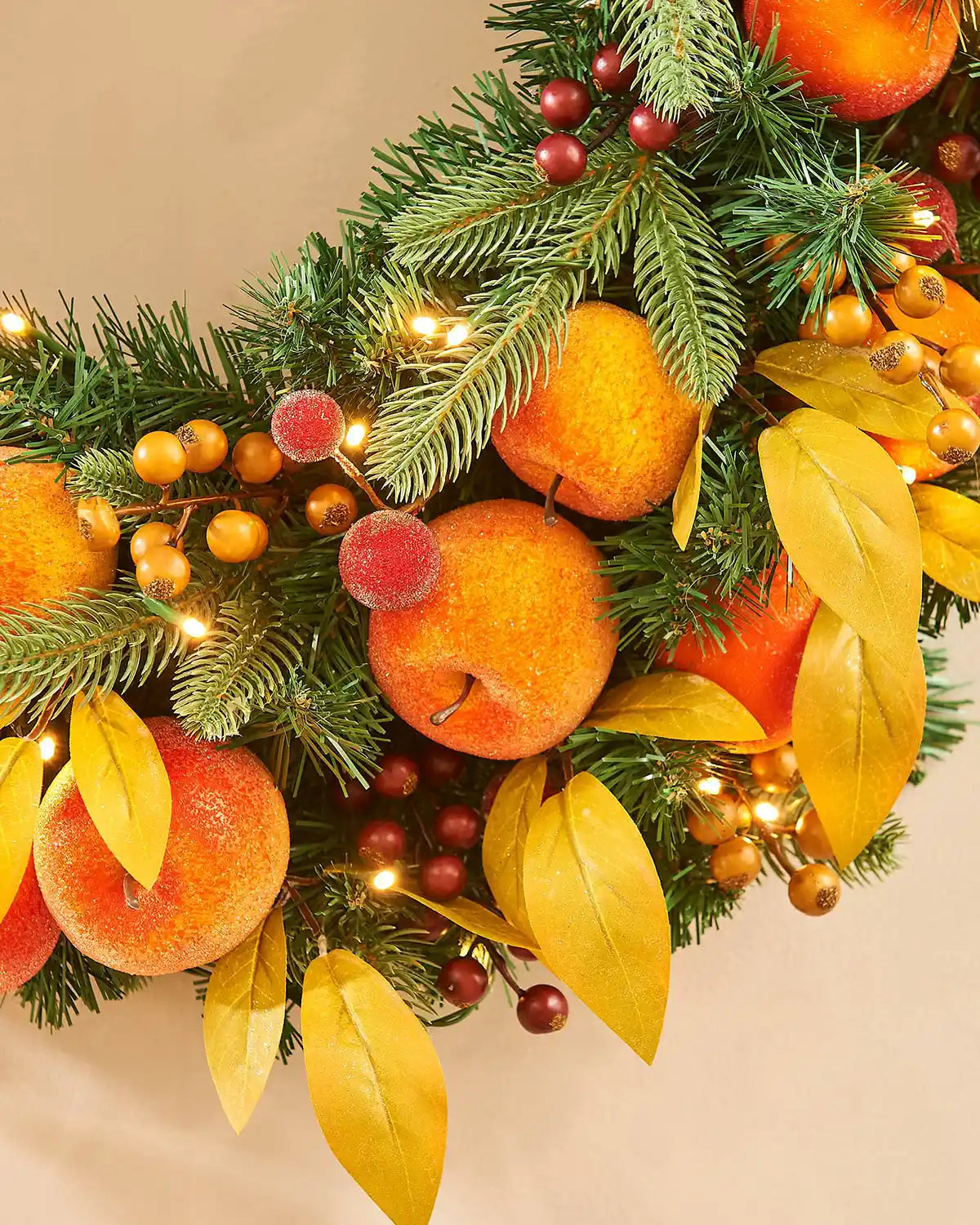 Bottom view of Artificial Oranges and peaches on a wreath against a cream background