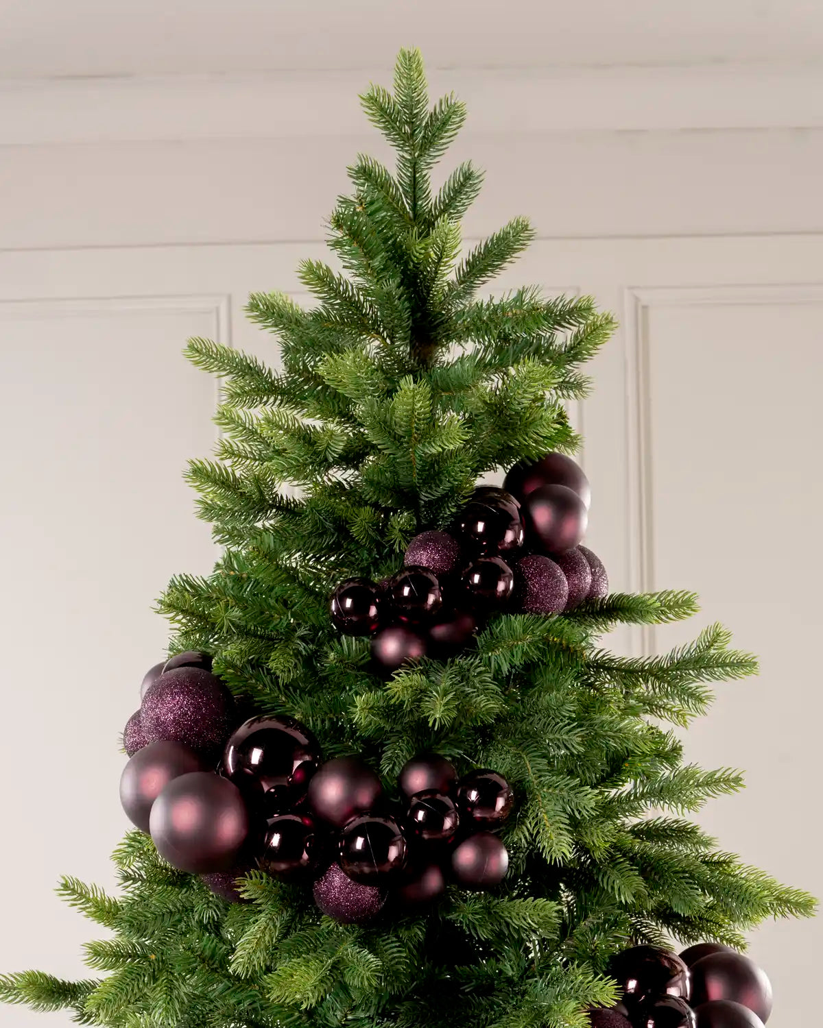 Burgundy Bauble Cluster Arch wrapped around a Christmas tree, showing clusters of burgundy baubles in different sizes and finishes