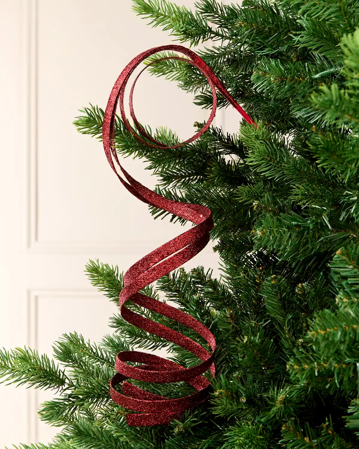 Burgundy Glitter Spiral Swirl Pick hanging from Christmas tree branch with cream background
