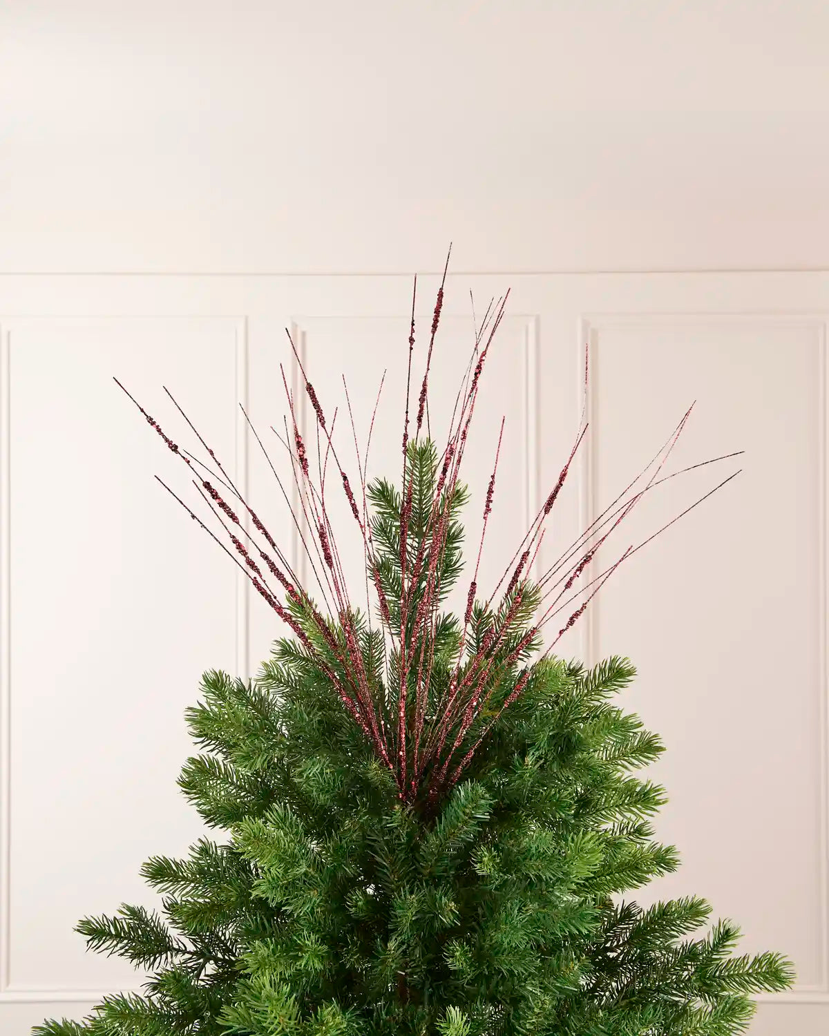 Burgundy Glitter Wispy Spray displayed at the top of a Christmas tree, with thin glitter-covered stems extending upward and outward
