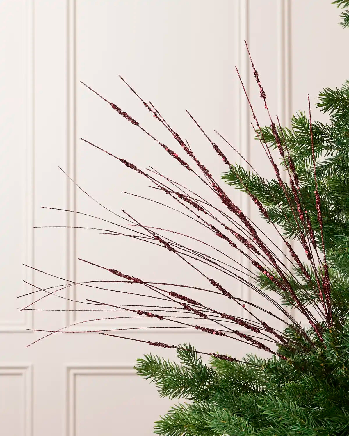 Burgundy Glitter Wispy Spray with long, slender glitter-covered stems arranged in a fan shape on a Christmas tree
