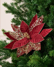 Burgundy & Gold glitter artificial poinsettia flower displayed on a Christmas tree, featuring layered pointed petals with gold glitter outlining the edges and veins and a sparkling gold center.
