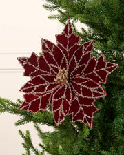 Burgundy and gold poinsettia flower on a Christmas tree against a cream background