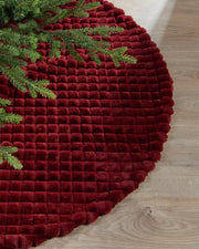 Close-up of burgundy diamond faux fur tree skirt on light wooden flooring, highlighting the soft texture 