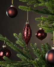 Burgundy glass ornaments on a Christmas tree with a dark background