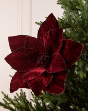 Burgundy oversized velvet artificial poinsettia displayed on a Christmas tree, featuring layered velvet petals with glittered edges and a sparkling center
