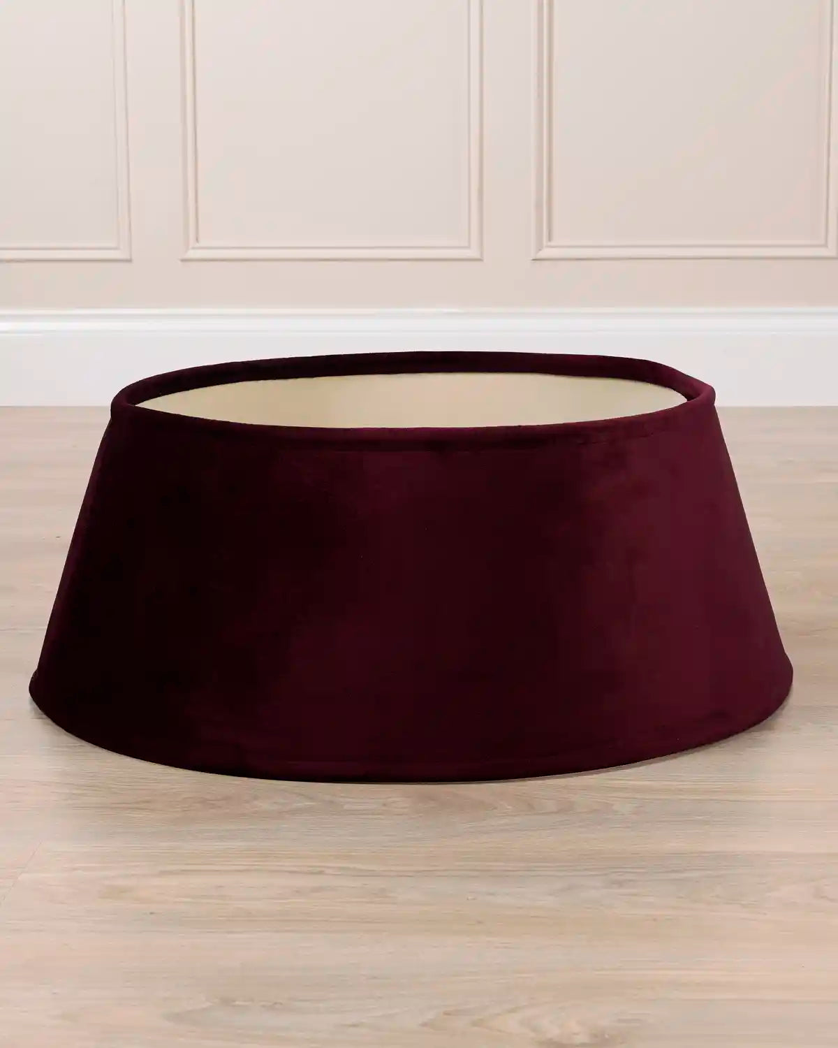 Burgundy velvet tree skirt displayed by itself, showing its circular shape, flared silhouette, and open center.