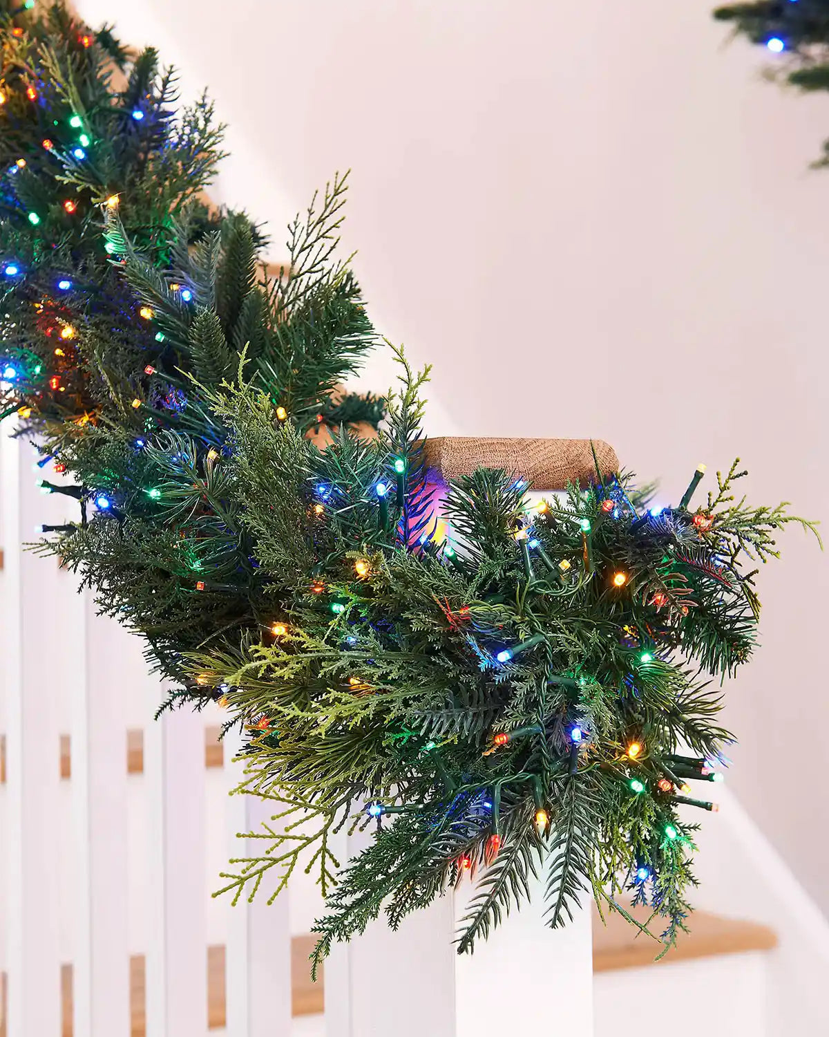 Christmas garland with colourful lights on a wooden staircase banister on a white background