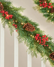 Christmas garland with greenery, red berries, and pinecones on a neutral background