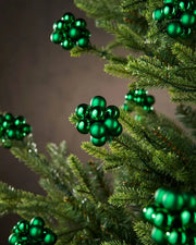 Christmas green berry cluster baubles on a Christmas tree branch with a brown background