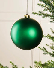 Christmas green oversized 15cm bauble on a Christmas tree branch