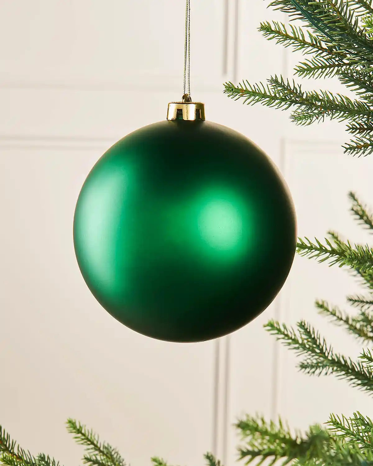 Christmas green oversized 15cm bauble on a Christmas tree branch