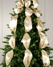 Decorative Christmas tree with latte ribbons against a white wall.
