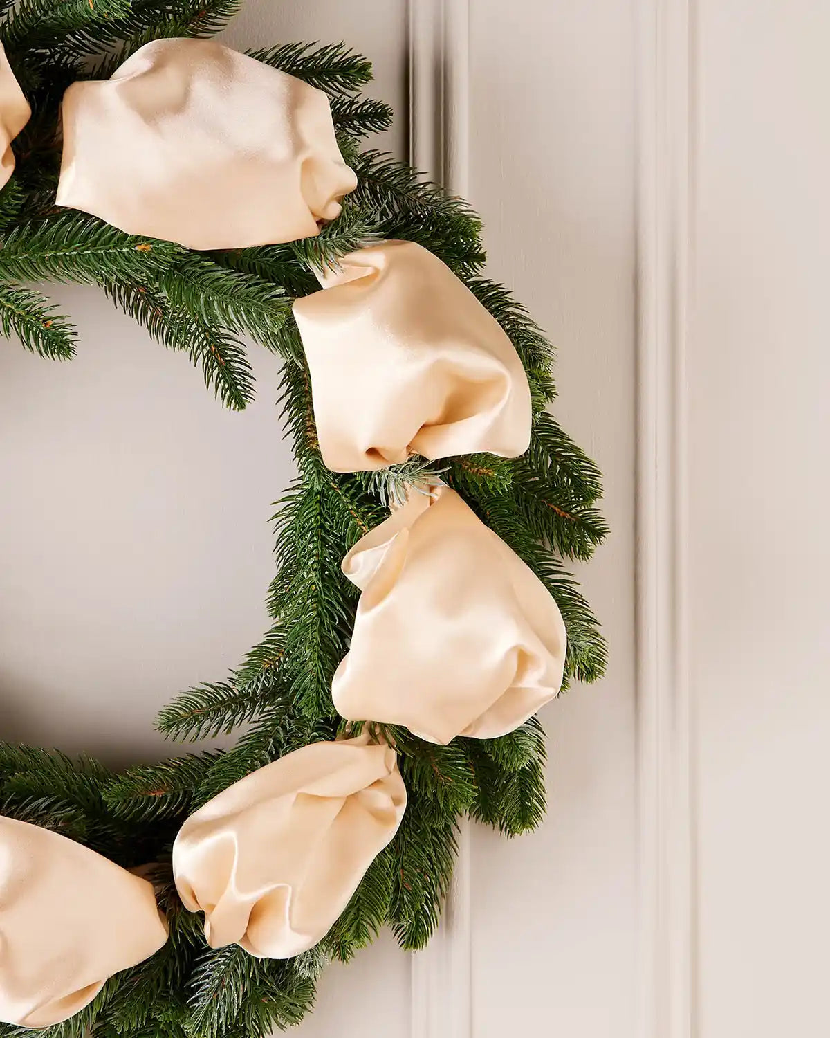 Christmas wreath with latte ribbons on a white door