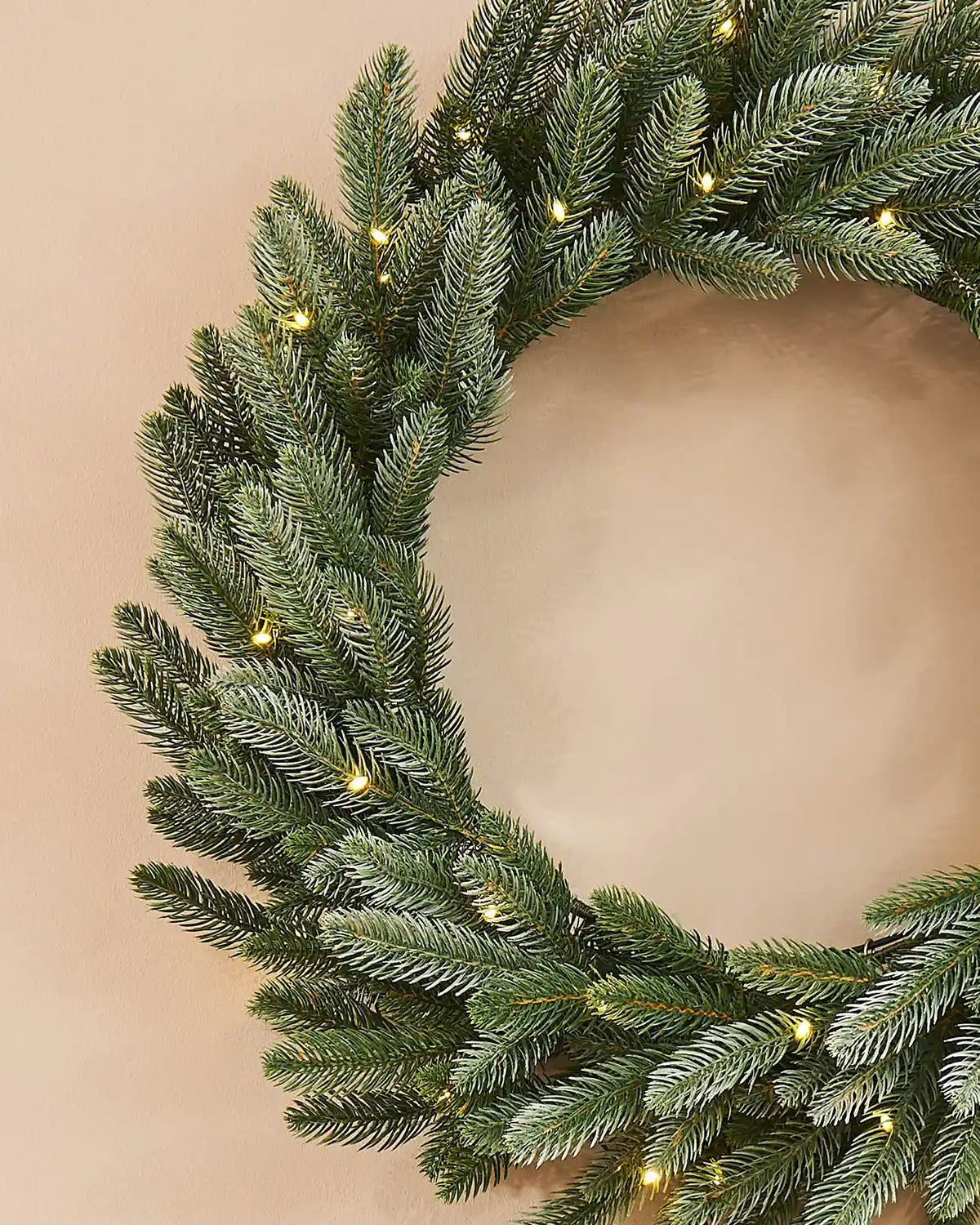 Christmas wreath with lights on a beige background