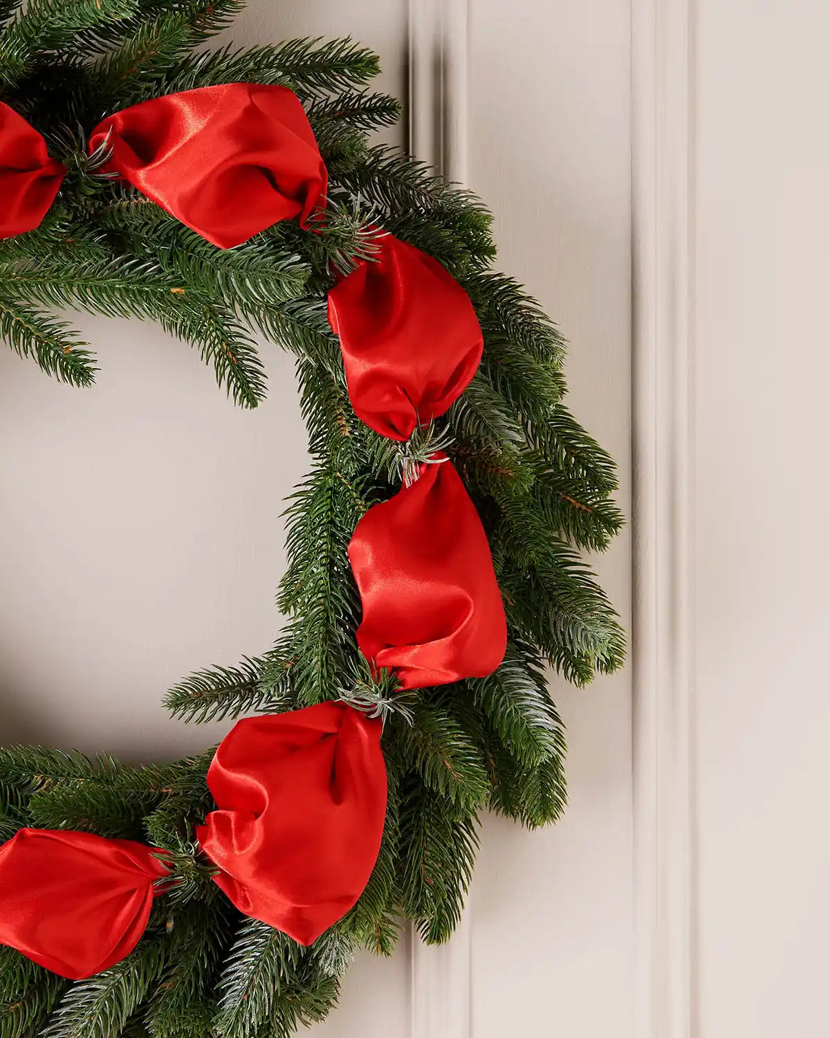 Christmas wreath with red ribbons on a neutral background