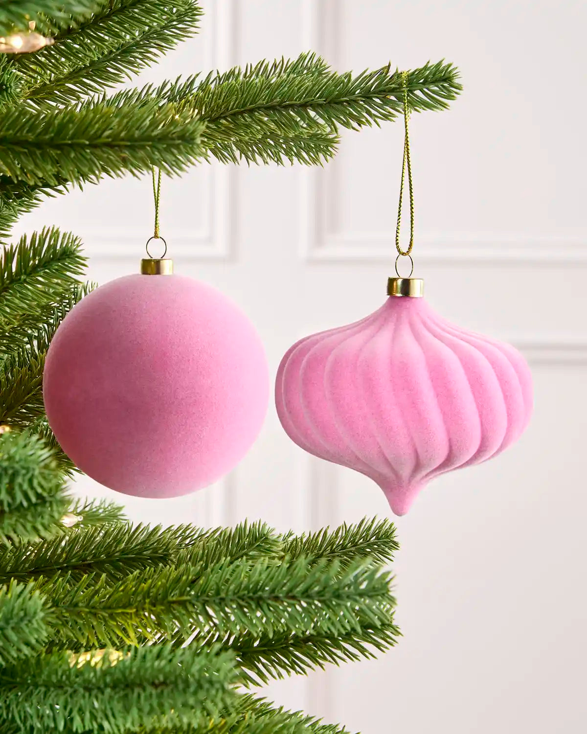 Close-up Pink velvet round and onion shape bauble hanging from Christmas tree branch.