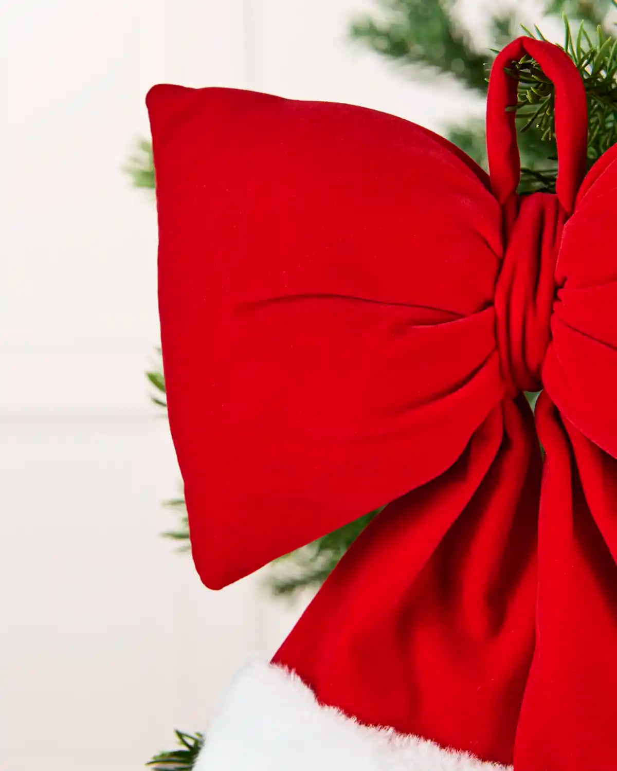 Close-up Red and white velvet Santa bow hanging from Christmas tree branch
