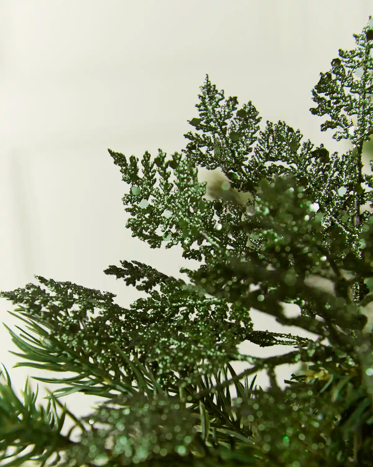 Close-up Sage green Glitter Leaf Pick placed in a Christmas tree
