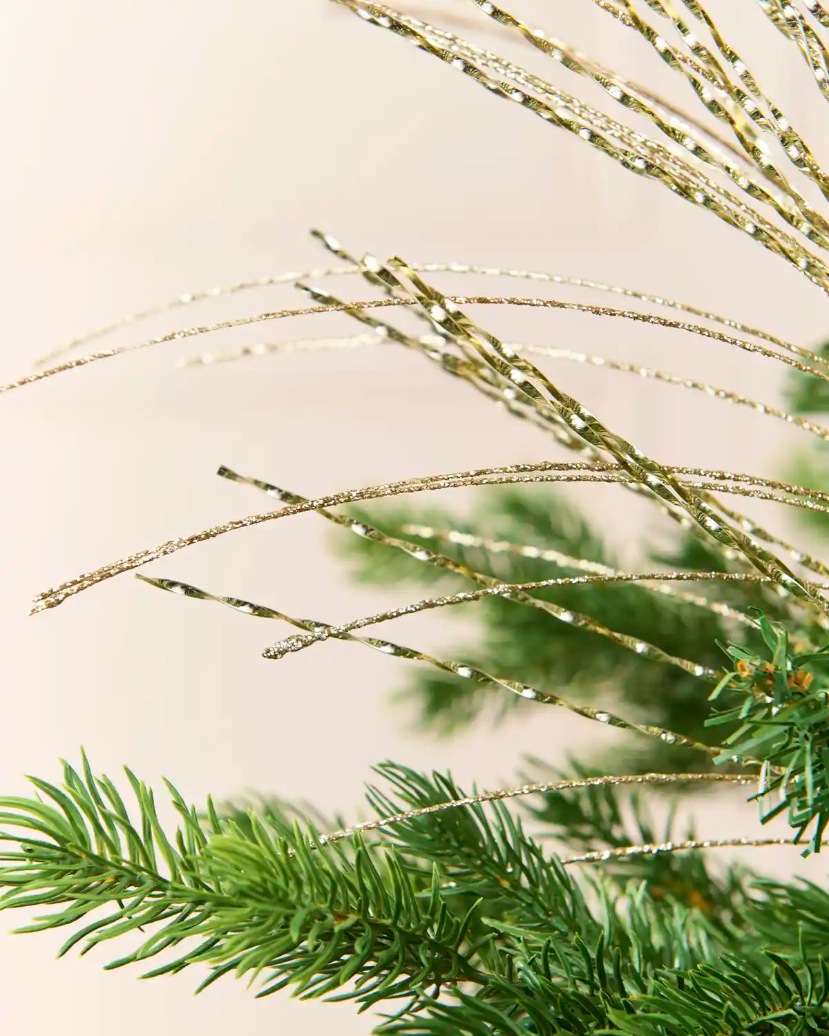 Close-up detail of the gold Glitter Fountain Christmas Tree Spray, highlighting its delicate glittered strands