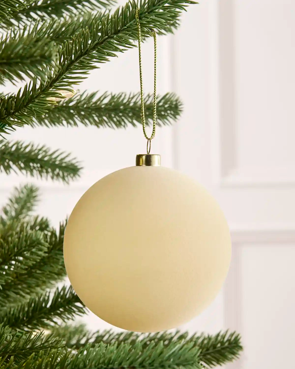 Close-up latte velvet round shape bauble hanging from Christmas tree