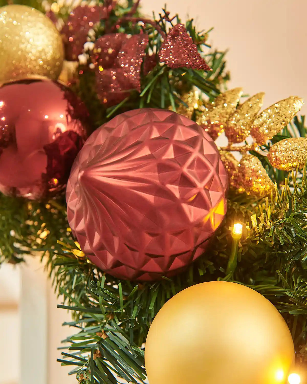 Close-up of Christmas ornaments on a tree with burgundy and gold baubles