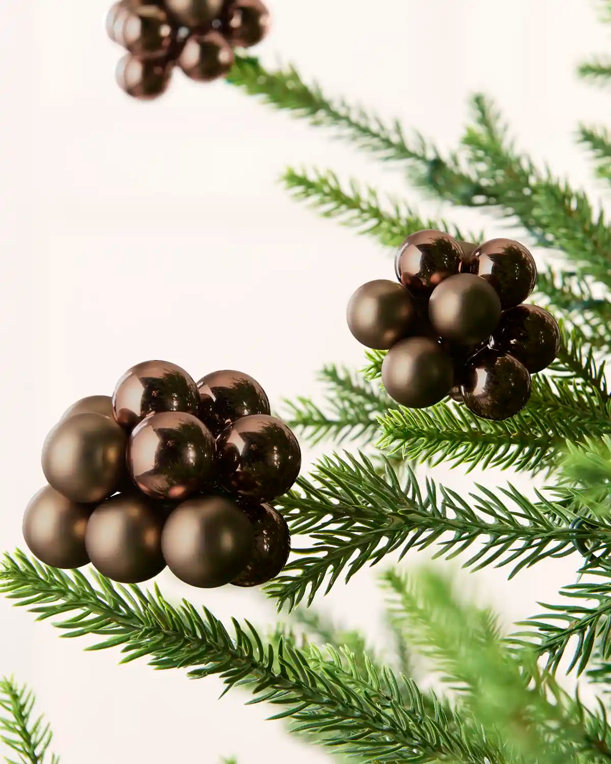 Close-up of Espresso glass berry cluster baubles with shiny and matt finishes on a Christmas tree.
