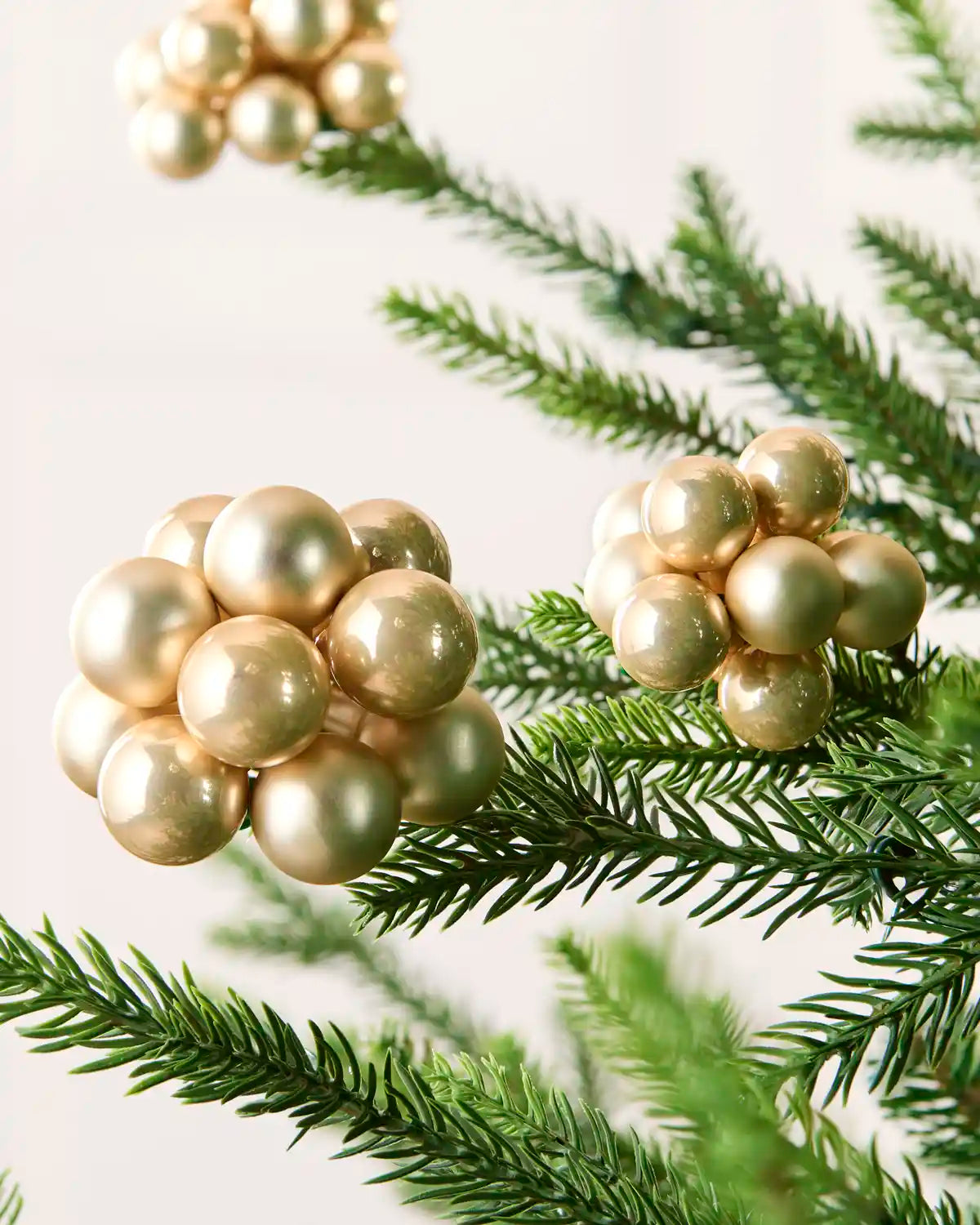 Close-up of Latte glass berry cluster baubles with shiny and matt finishes on a Christmas tree.
