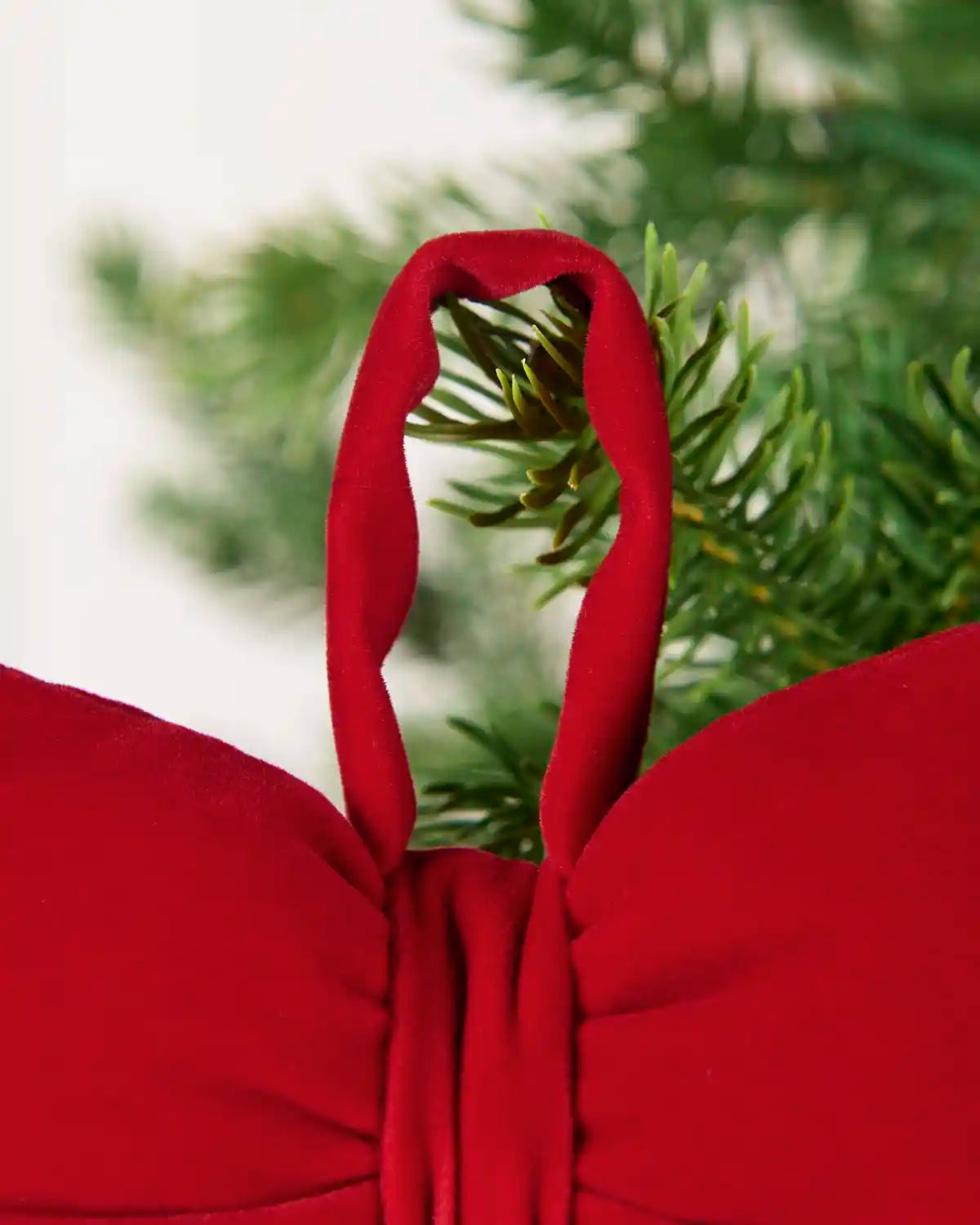 Close-up of Red hanging loop on a Christmas tree branch tip.