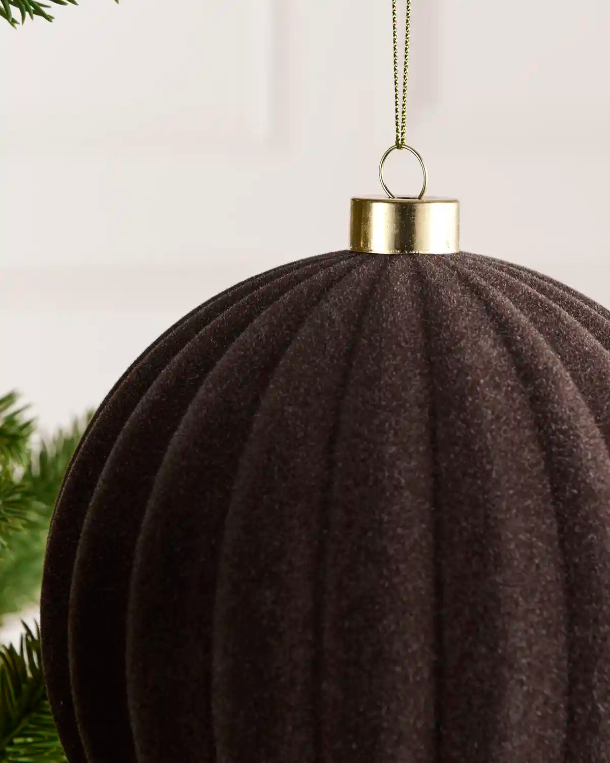 Close-up of a 15 cm Espresso velvet Ribbed bauble showing its Ribbed texture and gold hanging cap.
