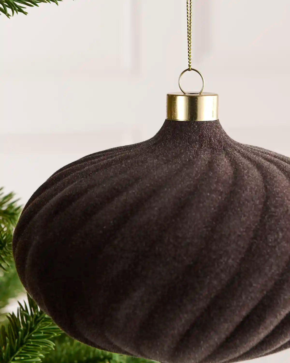 Close-up of a 15 cm Espresso velvet Spiral bauble showing its Spiral texture and gold hanging cap.
