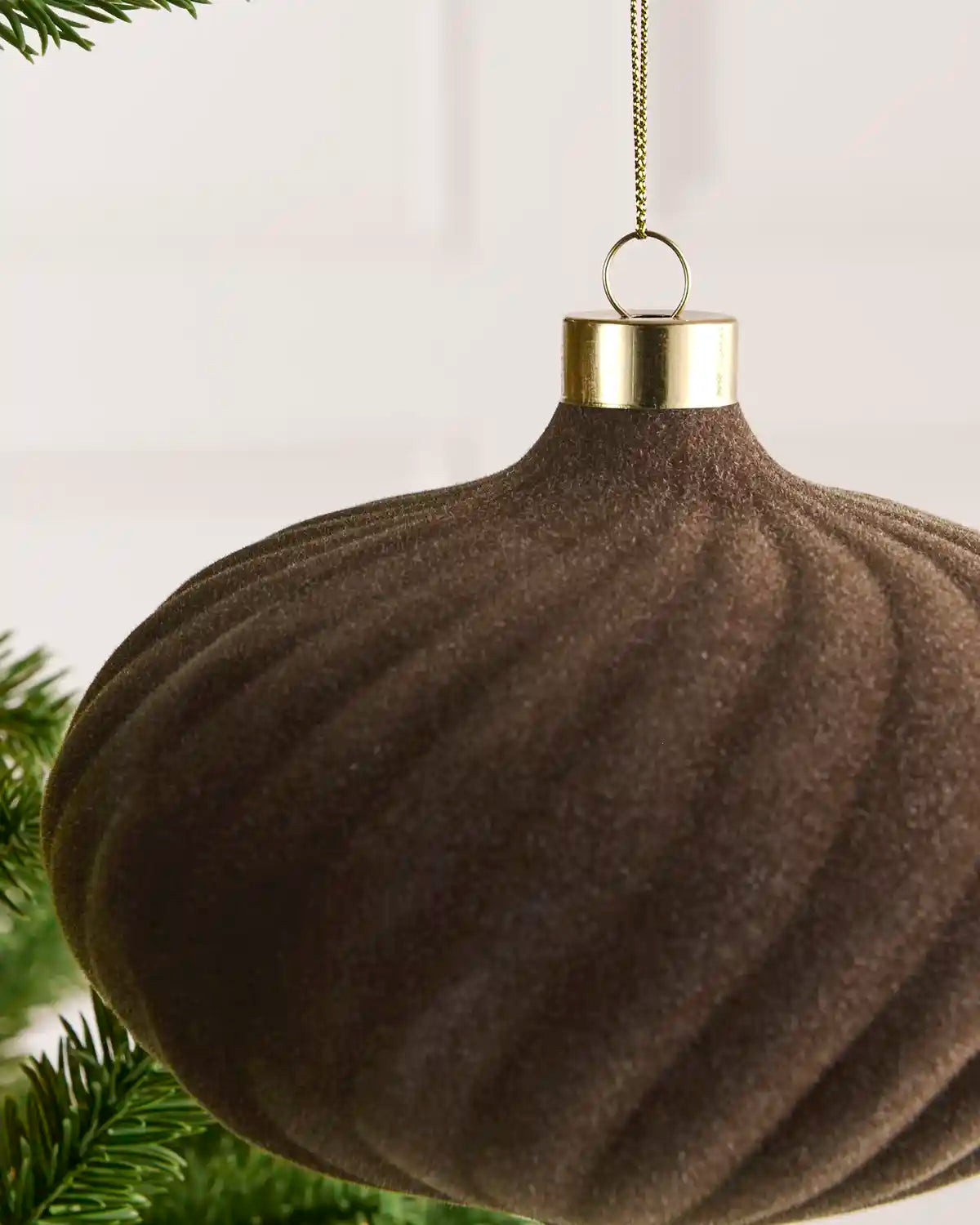 Close-up of a 15 cm Mocha velvet Spiral bauble showing its Spiral texture and gold hanging cap.
