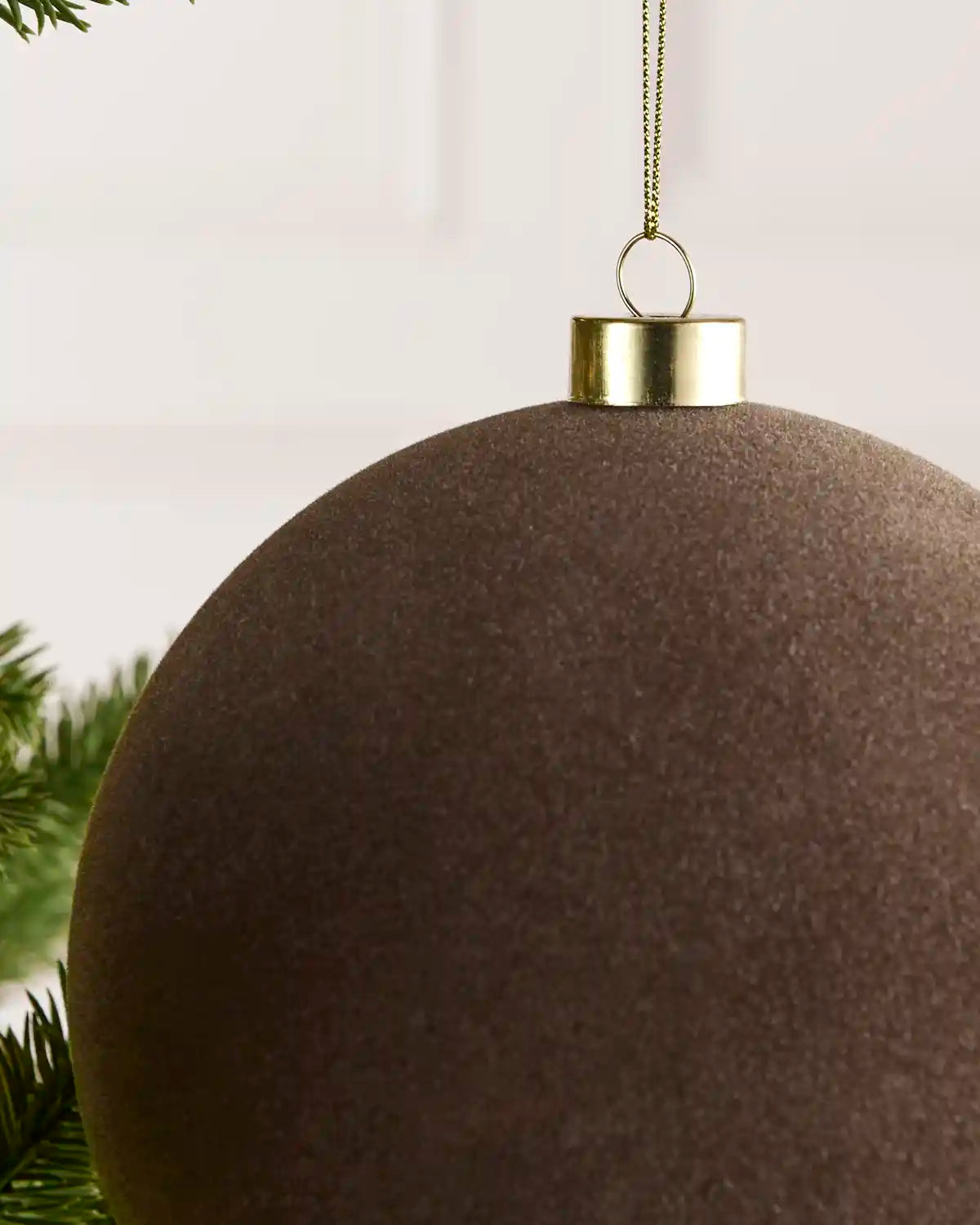 Close-up of a 15 cm Mocha velvet Traditional bauble showing its smooth texture and gold hanging cap.
