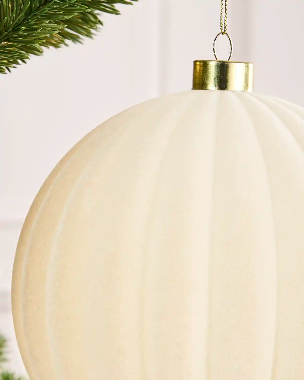 Close-up of a 15 cm latte velvet Ribbed bauble showing its ribbed texture and gold hanging cap.
