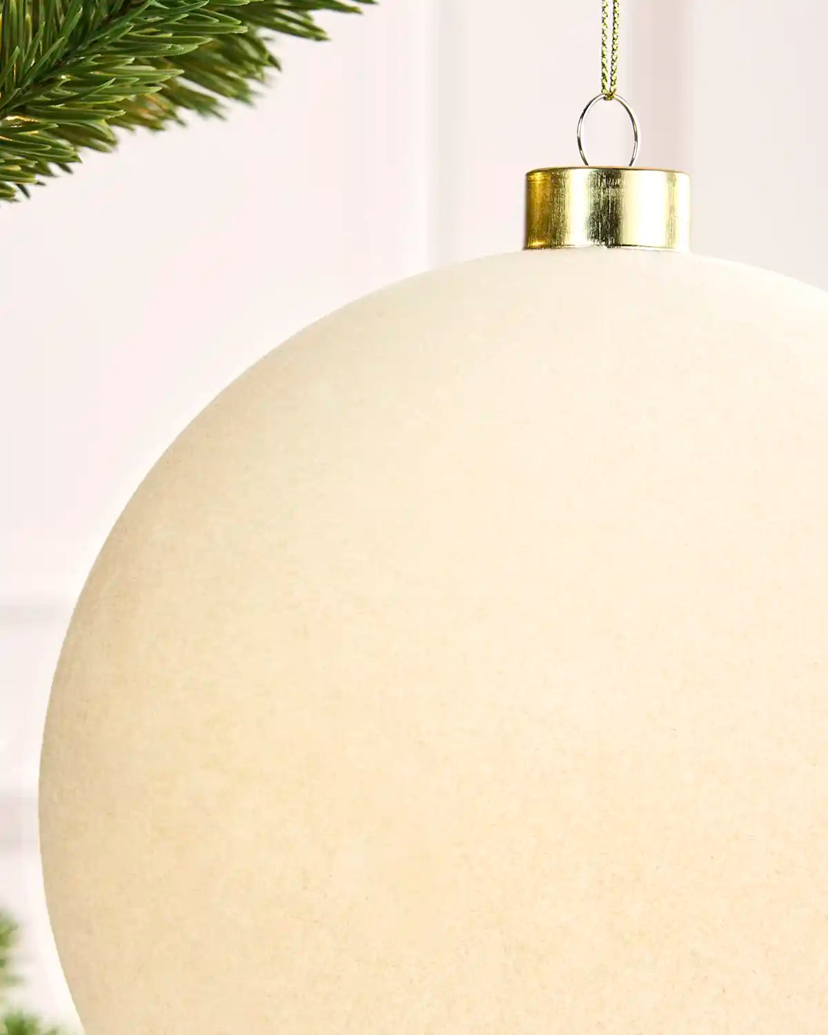 Close-up of a 15 cm latte velvet traditional bauble showing its smooth texture and gold hanging cap.